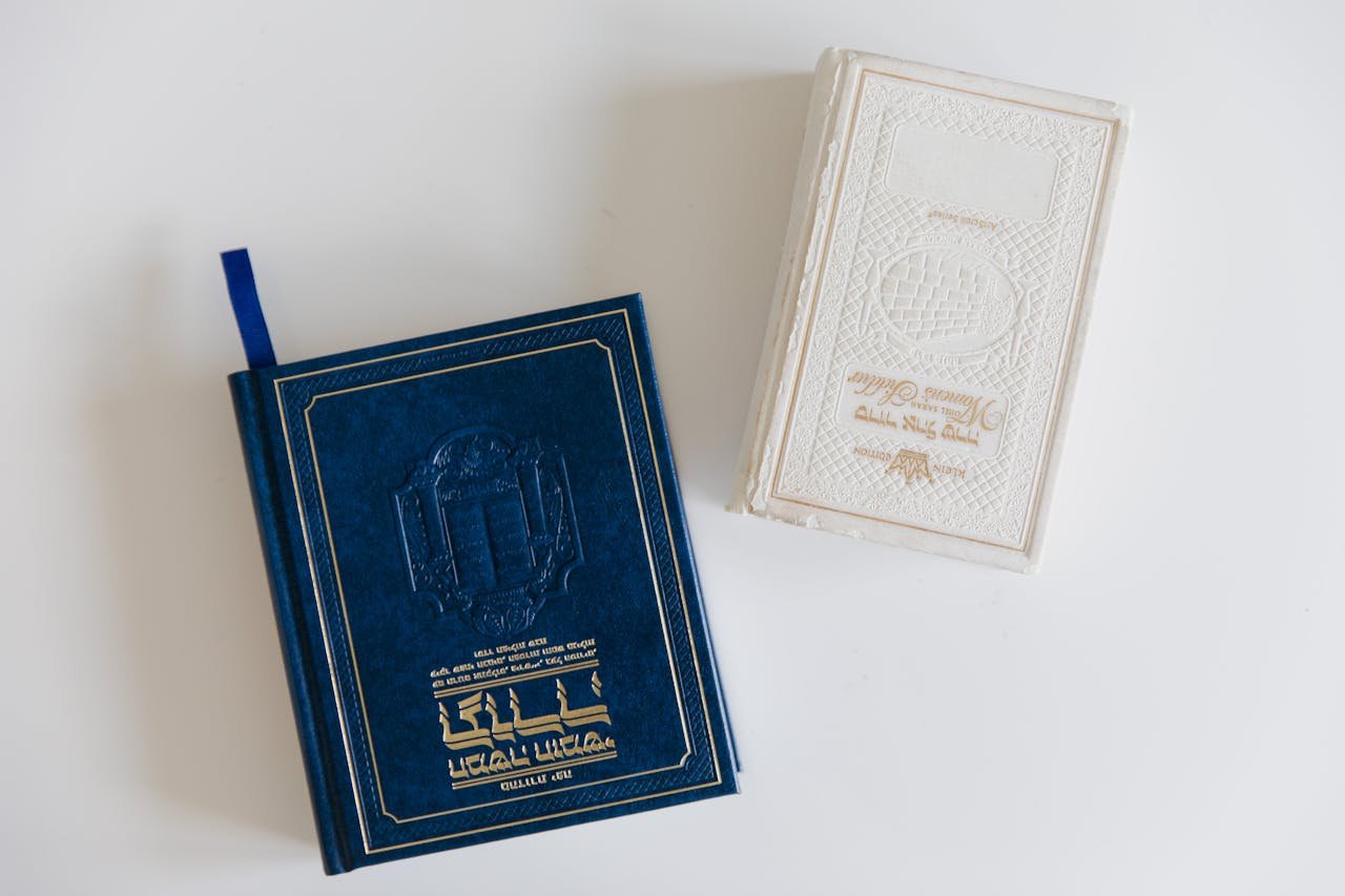 Close-up of two religious books with intricate covers on a white background.